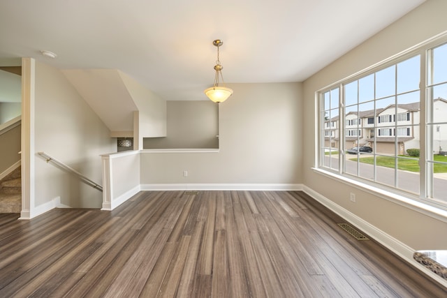 unfurnished living room with dark wood-style flooring, visible vents, and baseboards