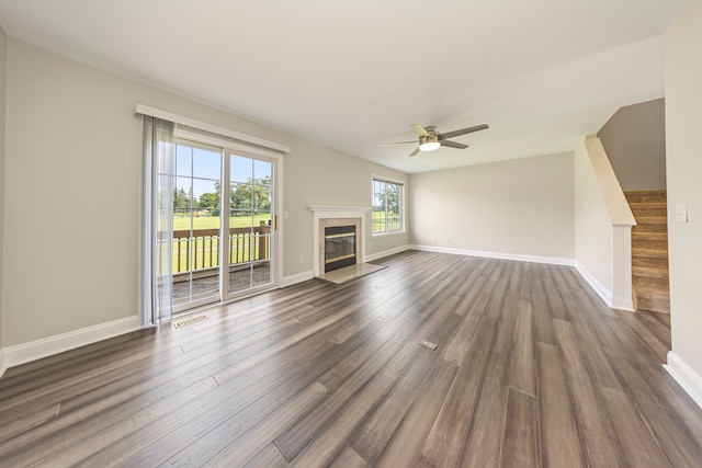 unfurnished living room with baseboards, dark wood-style floors, a fireplace with flush hearth, ceiling fan, and stairs