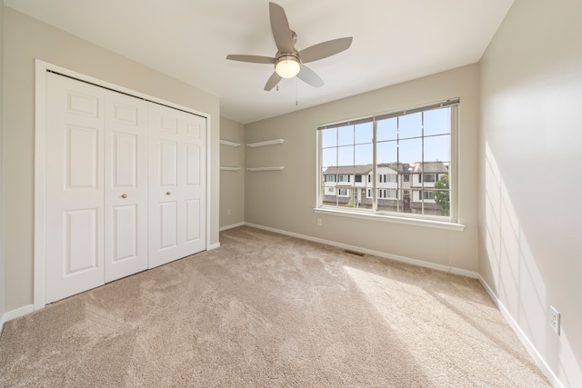 unfurnished bedroom with baseboards, visible vents, ceiling fan, carpet, and a closet