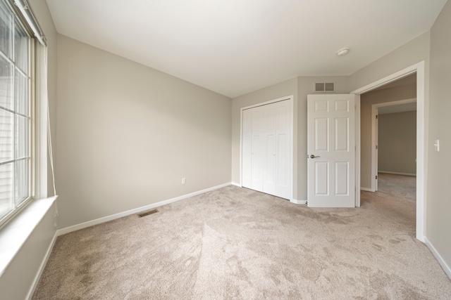 unfurnished bedroom with carpet floors, visible vents, and baseboards