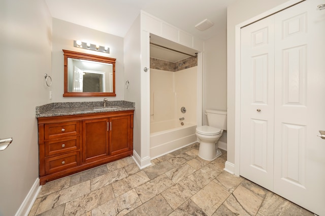 bathroom with baseboards, stone tile floors, vanity, and toilet