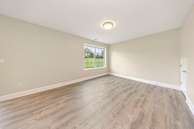 unfurnished room with light wood-type flooring and baseboards