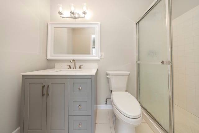 bathroom with baseboards, toilet, tile patterned flooring, vanity, and a shower stall