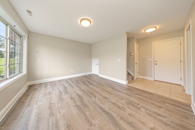 unfurnished room featuring baseboards, visible vents, light wood finished floors, and stairs