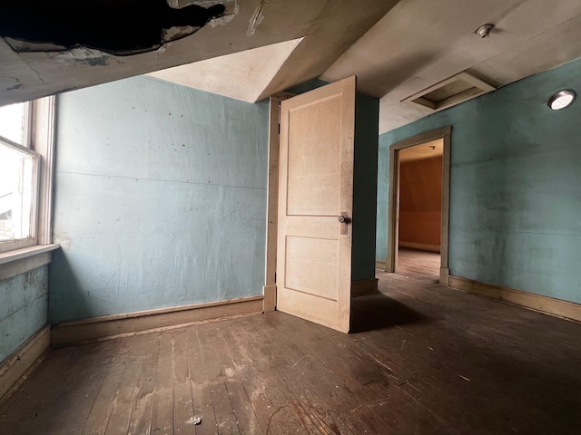 unfurnished room with attic access, visible vents, and dark wood finished floors