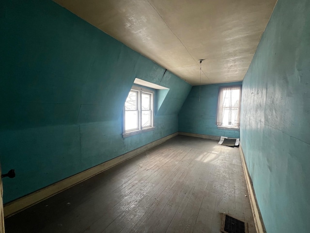 additional living space with lofted ceiling, visible vents, and hardwood / wood-style floors