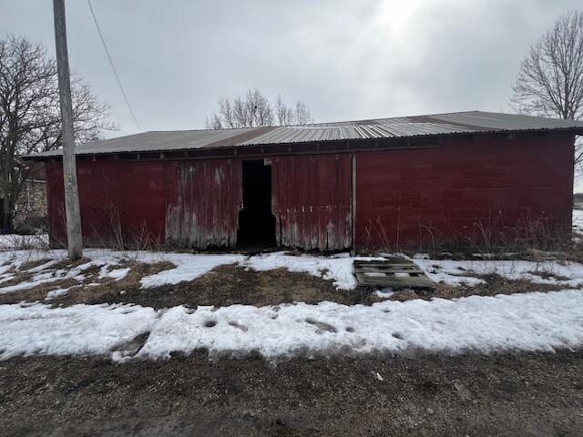 view of snow covered exterior with a detached garage, a pole building, metal roof, and an outdoor structure