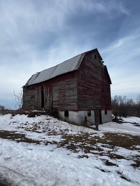 snow covered structure with a barn and an outbuilding