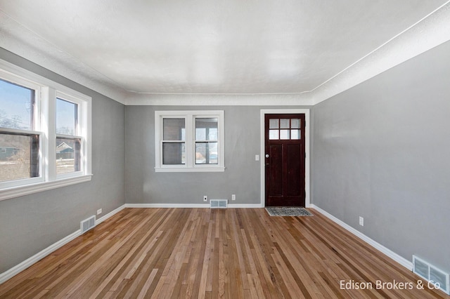 foyer entrance featuring a healthy amount of sunlight, wood-type flooring, and visible vents