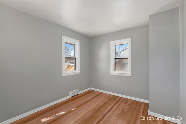 empty room featuring visible vents, baseboards, and wood finished floors