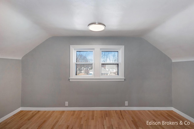 bonus room with lofted ceiling, baseboards, and wood finished floors