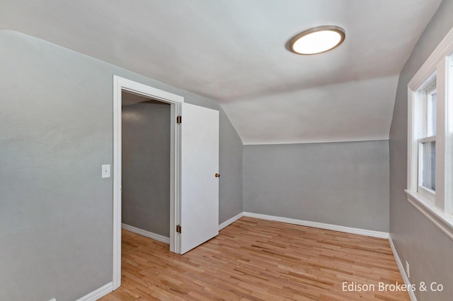 additional living space with baseboards, vaulted ceiling, and light wood finished floors