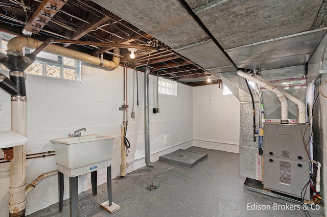 basement with a healthy amount of sunlight, a sink, and heating unit