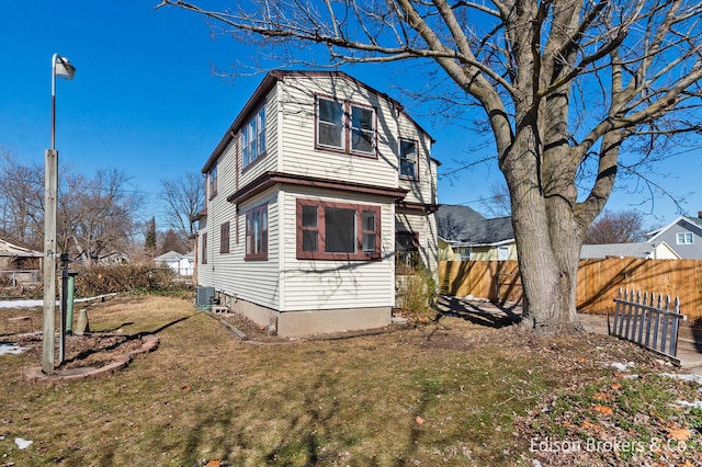 rear view of property featuring central air condition unit, fence, and a yard