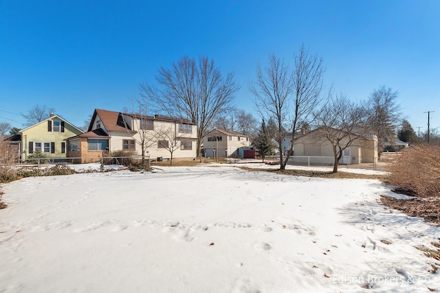 yard covered in snow featuring a garage, fence, and a residential view