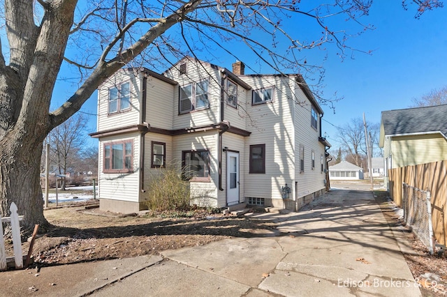 exterior space with entry steps, driveway, a chimney, and fence