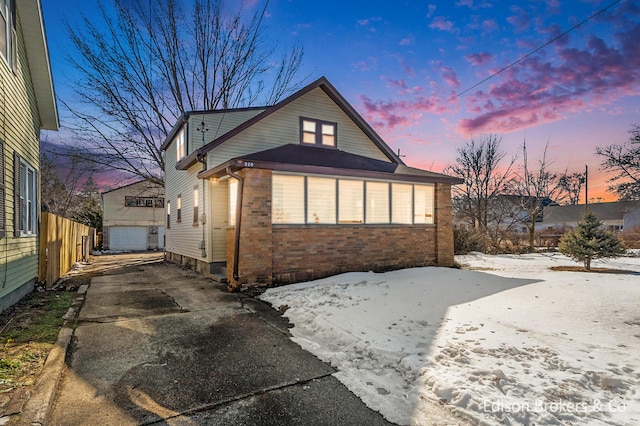 view of front facade featuring fence, concrete driveway, and brick siding