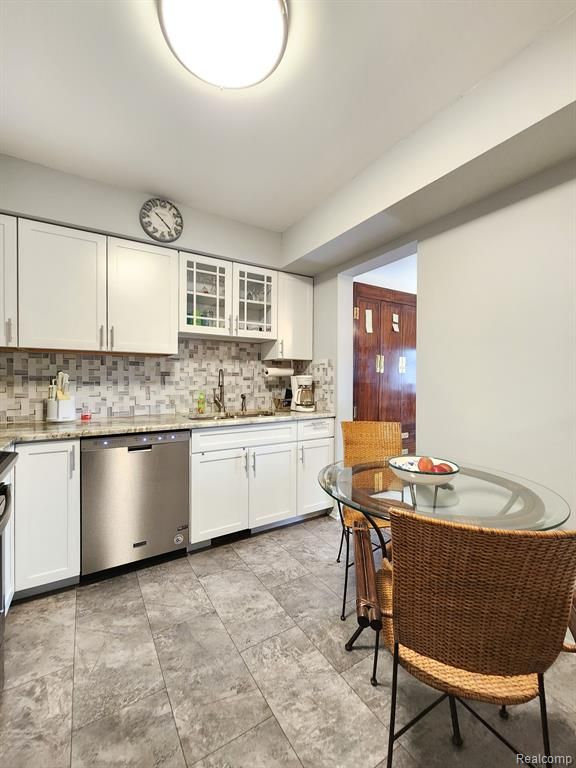 kitchen with a sink, glass insert cabinets, white cabinets, and dishwasher