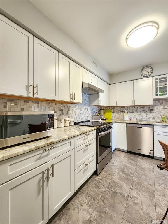 kitchen featuring stainless steel appliances, glass insert cabinets, and white cabinetry