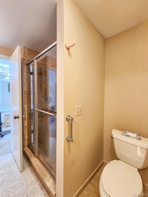 full bathroom with a stall shower, baseboards, toilet, and tile patterned floors