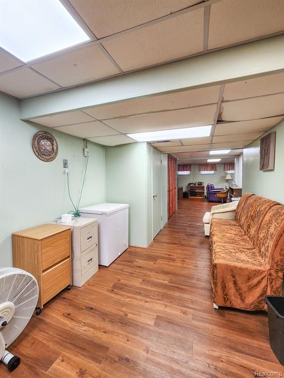 interior space with a paneled ceiling, fridge, and wood finished floors