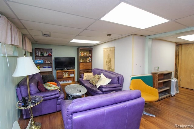 living area featuring a paneled ceiling and wood finished floors