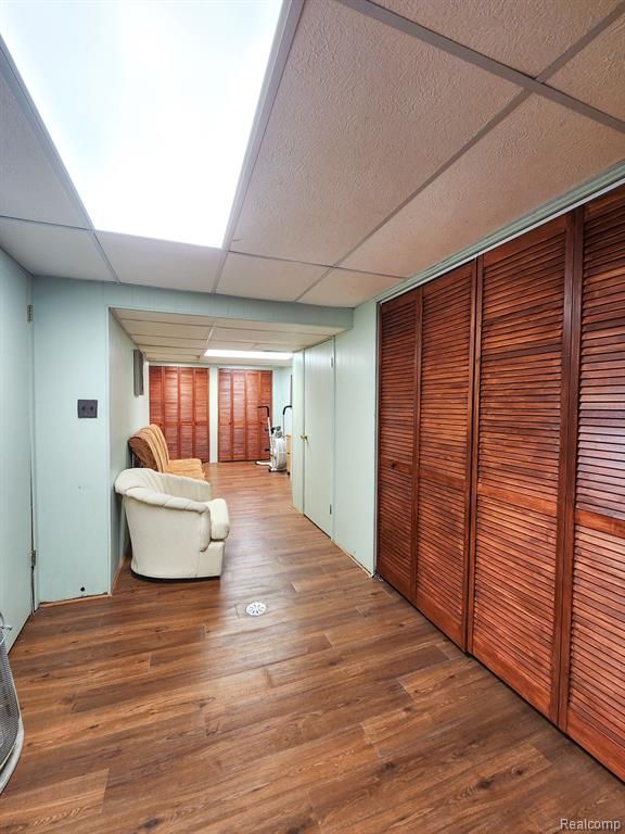 corridor with a drop ceiling and wood finished floors