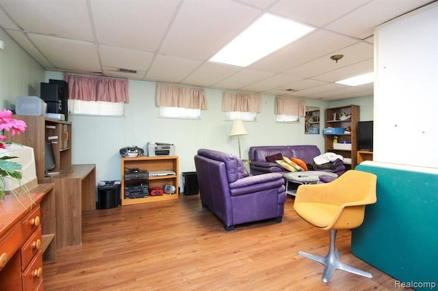 living area with light wood finished floors and a drop ceiling