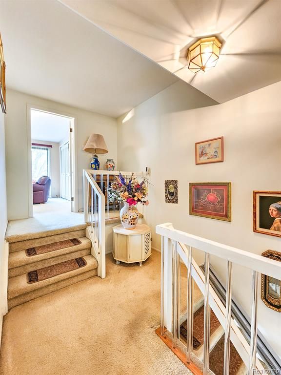 hall with carpet floors and an upstairs landing