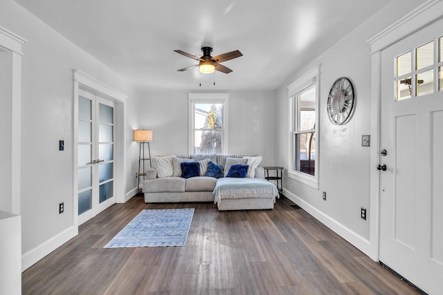 living room with ceiling fan, baseboards, and dark wood-style flooring