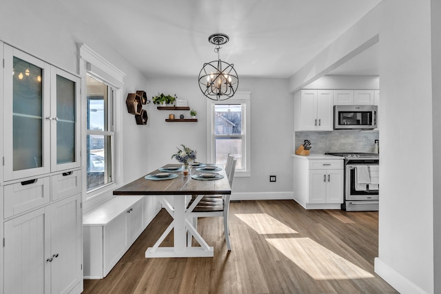 dining area with baseboards, light wood-style flooring, and a notable chandelier