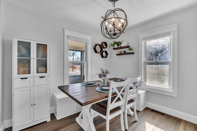 dining space featuring baseboards, a notable chandelier, visible vents, and dark wood-type flooring