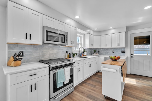 kitchen featuring white cabinets, butcher block counters, stainless steel appliances, and a sink