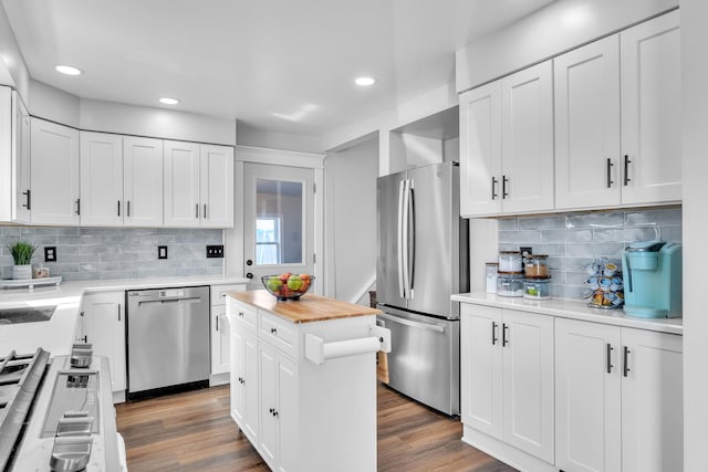 kitchen with appliances with stainless steel finishes, a center island, white cabinets, and dark wood finished floors