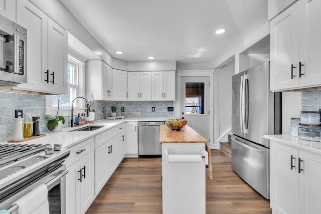 kitchen with stainless steel appliances, white cabinets, wooden counters, and a kitchen island