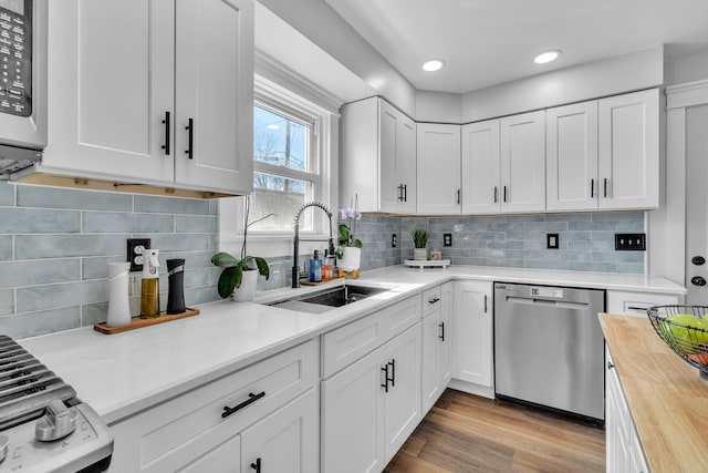 kitchen featuring stainless steel appliances, white cabinetry, a sink, and wood counters