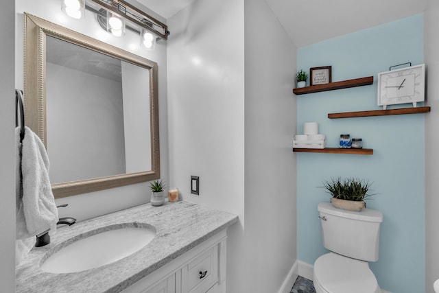 bathroom with toilet, baseboards, and vanity