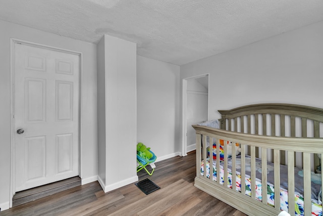 bedroom featuring baseboards, visible vents, dark wood finished floors, and a textured ceiling