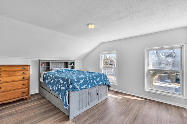 bedroom with lofted ceiling, baseboards, dark wood finished floors, and a textured ceiling