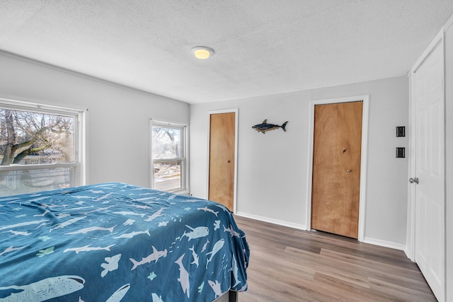 bedroom featuring a textured ceiling, wood finished floors, and baseboards