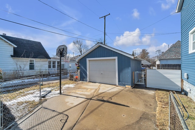 detached garage featuring concrete driveway and fence