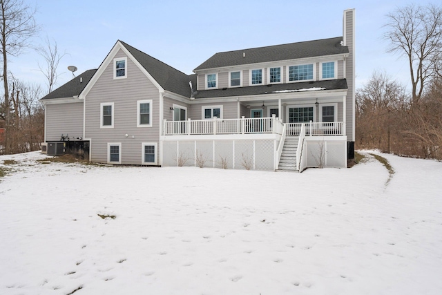 snow covered back of property featuring a porch, cooling unit, a chimney, and stairs