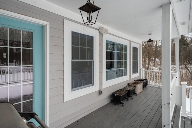 snow covered deck featuring covered porch