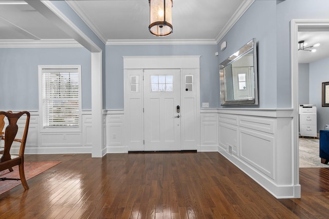 foyer with dark wood-style floors, wainscoting, plenty of natural light, and ornamental molding