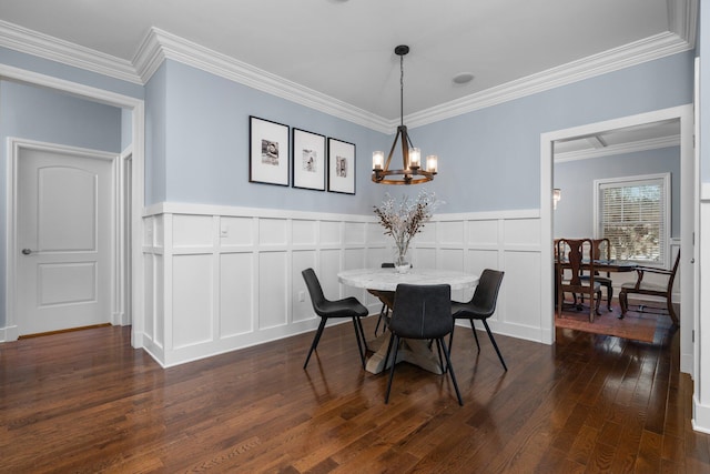 dining area with a decorative wall, a wainscoted wall, a notable chandelier, ornamental molding, and dark wood finished floors