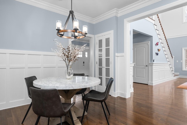 dining area featuring a chandelier, dark wood-style flooring, a decorative wall, and stairs