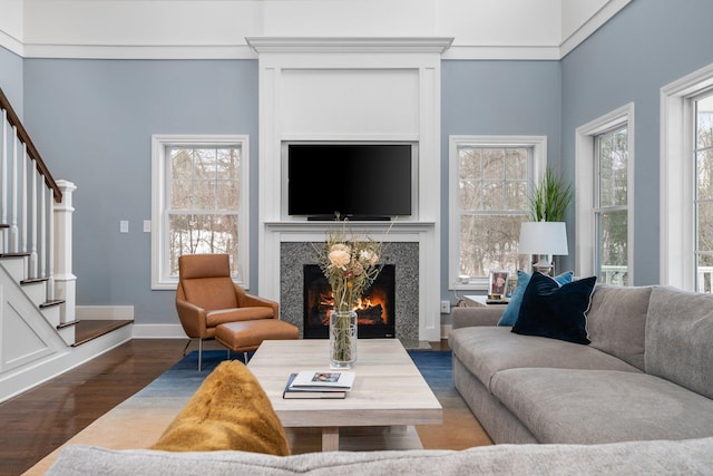 living room with stairs, dark wood-type flooring, plenty of natural light, and a high end fireplace