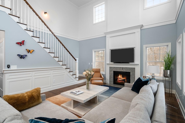 living room with ornamental molding, dark wood-type flooring, stairway, and a healthy amount of sunlight