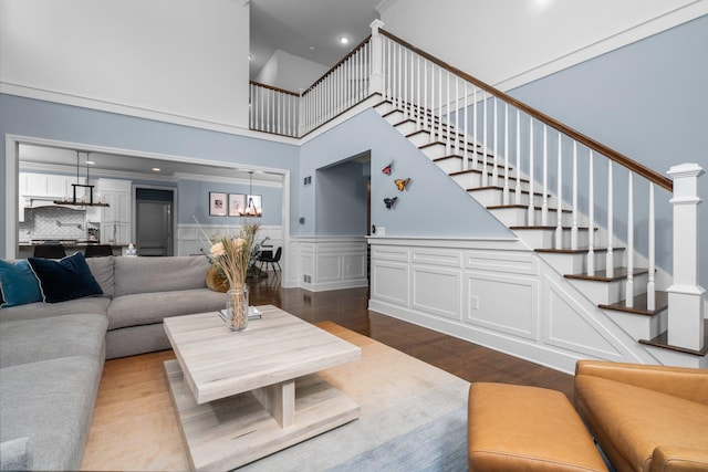 living area featuring a wainscoted wall, stairway, wood finished floors, and a decorative wall