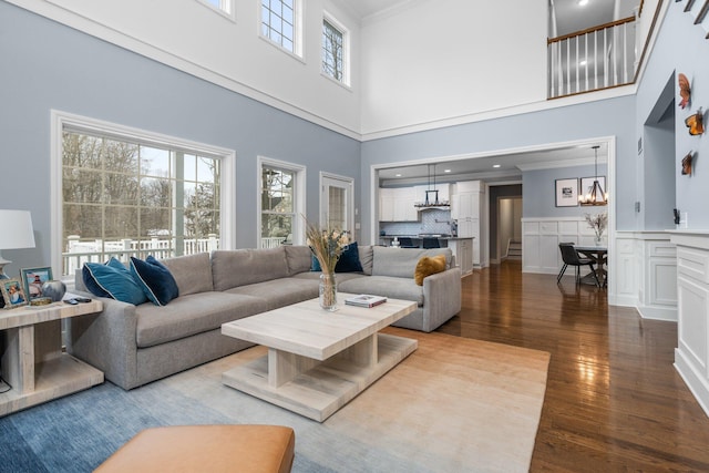 living room with ornamental molding, a wainscoted wall, a notable chandelier, and wood finished floors